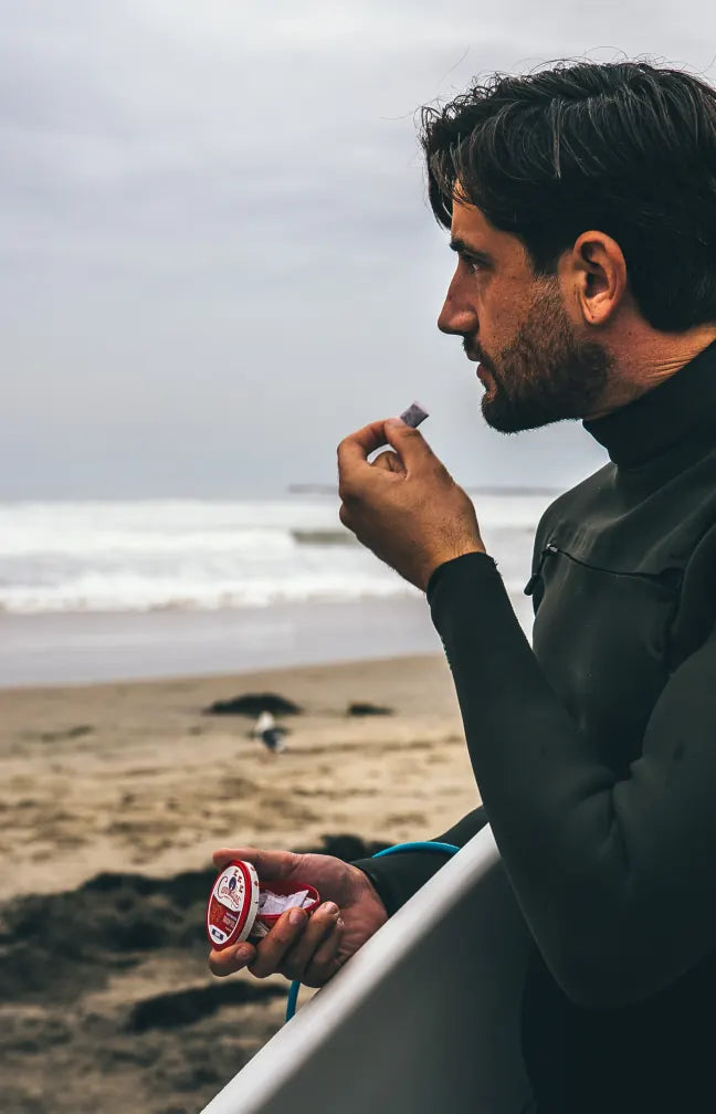 Surfer on the beach taking a pouch from a tin of Cannadips