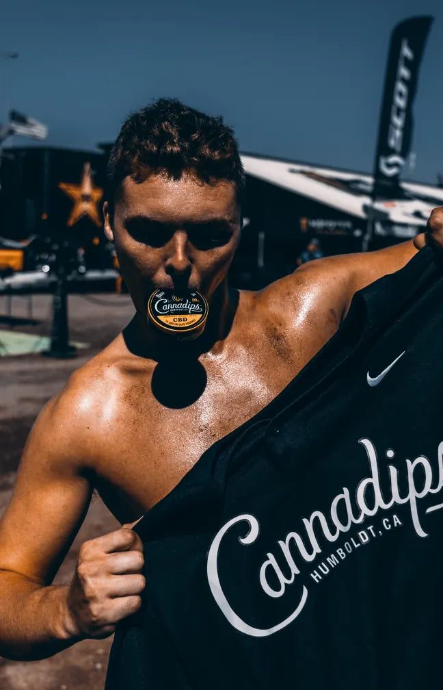 Athlete holding a Cannadips tin in his teeth and a Cannadips jersey