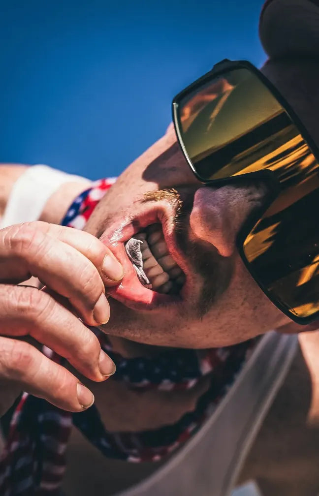 Guy in sunglasses tucking a Cannadips pouch into his lip